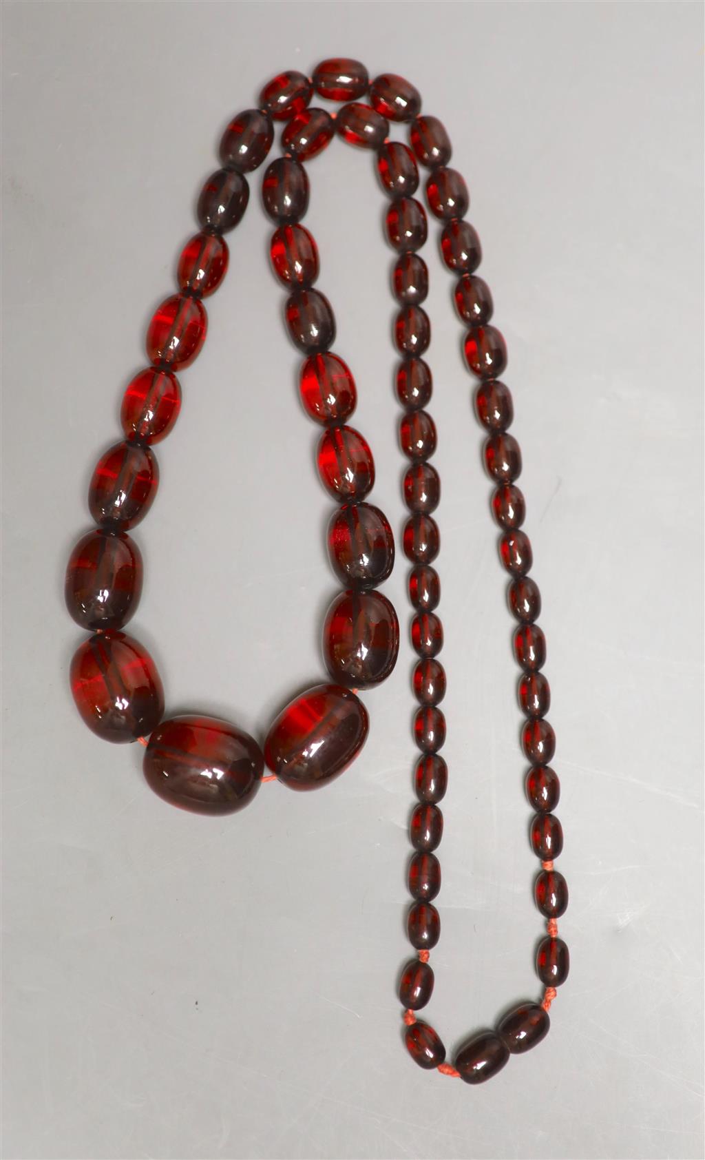 A single strand graduated oval simulated cherry amber bead necklace, 84cm, gross 90 grams.